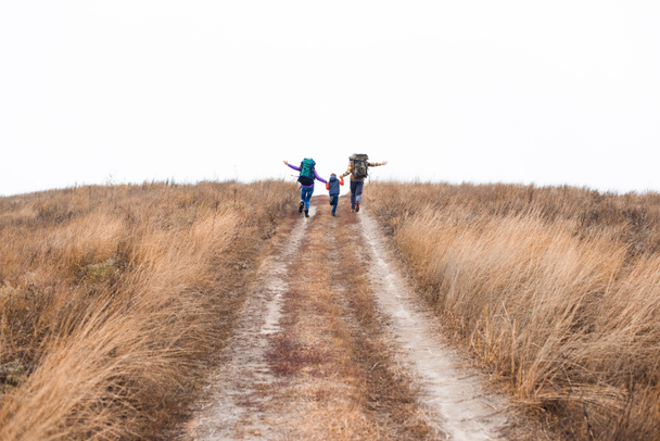 Family with backpacks running on rural path - Photo, Image