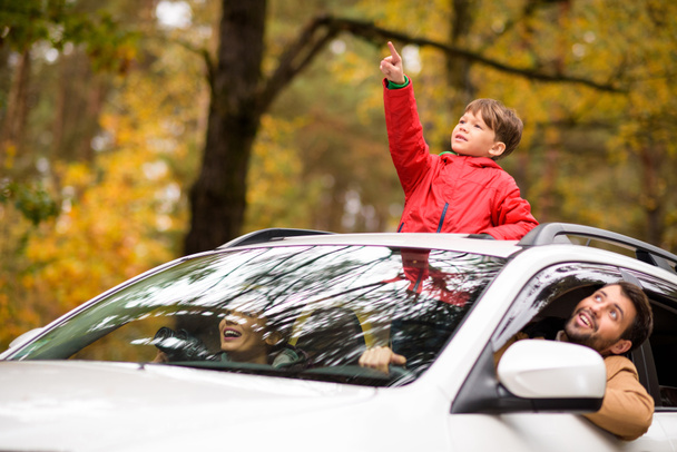 Adorable boy standing in car sunroof  - 写真・画像