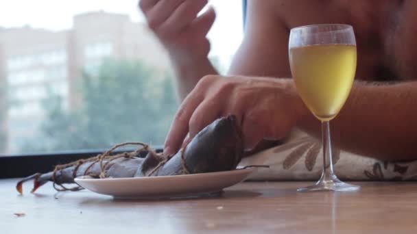 man drinking beer from a glass and eat fish, lying on the floor - Video