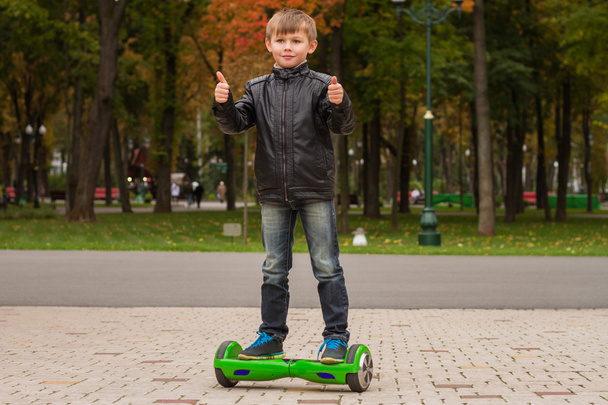 Garçon heureux debout sur hoverboard ou gyroscooter extérieur
.  - Photo, image