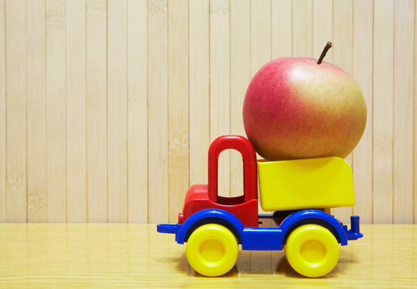 Toy plastic car with red apple - Zdjęcie, obraz