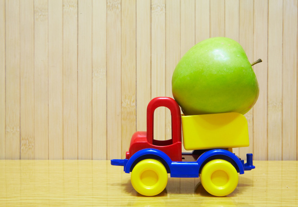 Toy plastic car with green apple - Фото, зображення