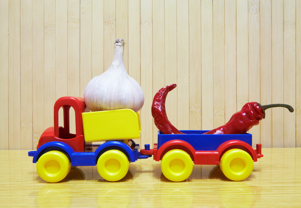 Toy plastic car with garlic and pepper - Fotoğraf, Görsel