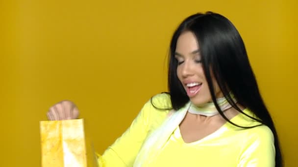 σέξι κορίτσι με τσάντα για ψώνια σε κίτρινο φόντο - Πλάνα, βίντεο