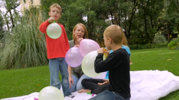 Children let their balloons fly away and one hits the camera - slowmo - Πλάνα, βίντεο