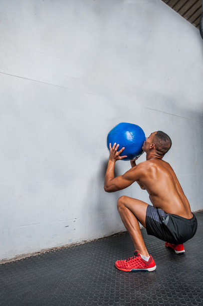 Yong atleta fazendo exercício de bola de parede no ginásio
 - Foto, Imagem