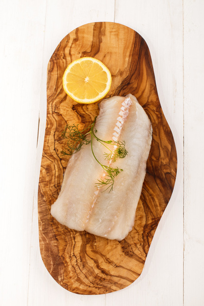 raw haddock with dill and lemon on a wooden board - Φωτογραφία, εικόνα