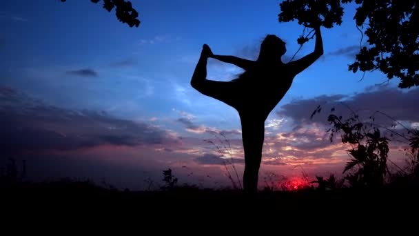 Silhouette Against Bright Color Sunset of One Young Graceful Girl Practicing Yoga Outdoors. - Πλάνα, βίντεο