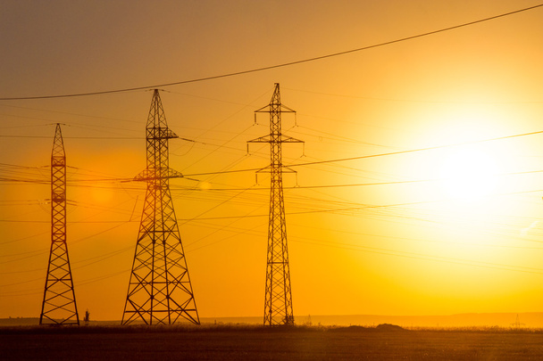 De lijn van de transmissie van de macht van de hoog-voltage. Energie pijlers. Bij zonsondergang, zonsopgang. hoogspanning - Foto, afbeelding