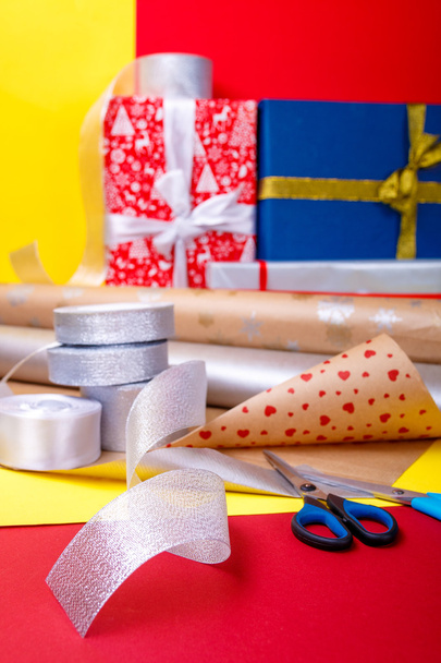 Geschenkverpackung, Schachteln, Papier, Schleife und Schere auf farbigem Hintergrund. Materialien Zubehör für Geschenke. Nahaufnahme. - Foto, Bild