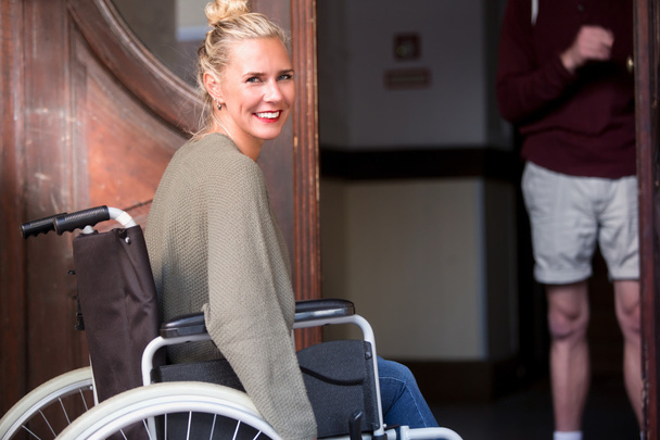 Frau im Rollstuhl vor Eingangstür - Foto, Bild