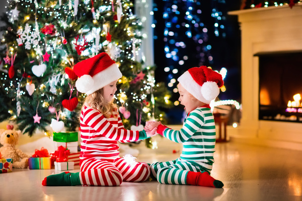 Kinder im Pyjama unterm Weihnachtsbaum - Foto, Bild