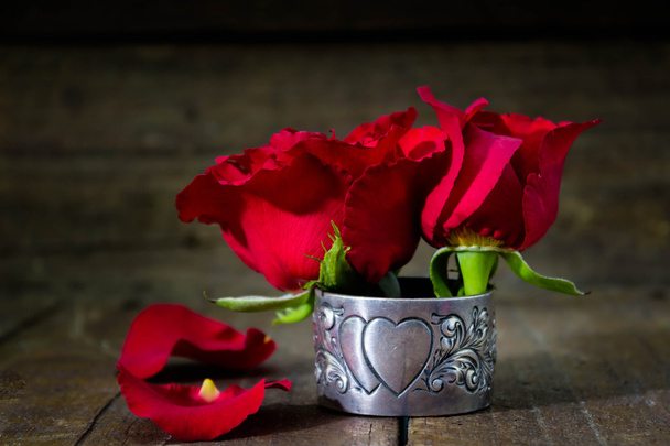 Fond romantique avec des roses courtes rouges sur une table en bois rustique
 - Photo, image