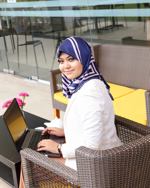 Asiática musulmana mujer pañuelo sentado al aire libre portátil sonrisa look f
 - Foto, imagen