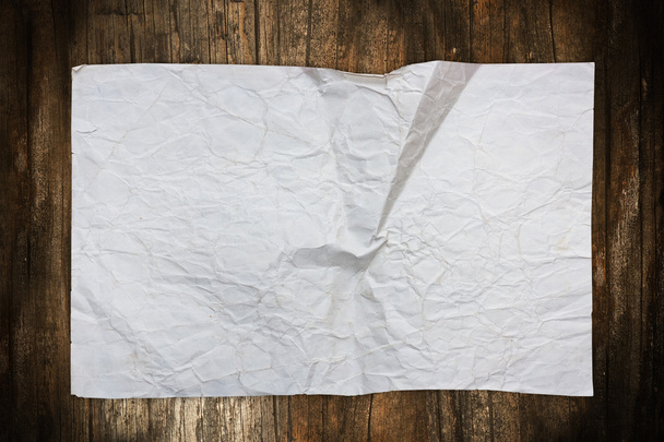 Wrinkled paper sheet on a dark wooden background - Fotoğraf, Görsel