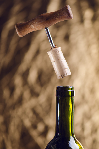Opening a wine bottle with a corkscrew on a golden background. Wine bottle with steam. Levitation of corkscrew. Isolated.  - Photo, Image