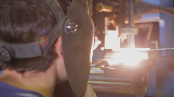 Worker controls plasma welding machine, welding metal parts. - Záběry, video