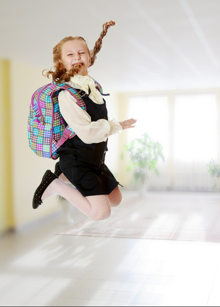 Girl schoolgirl with a satchel behind shoulders jumps - Fotoğraf, Görsel