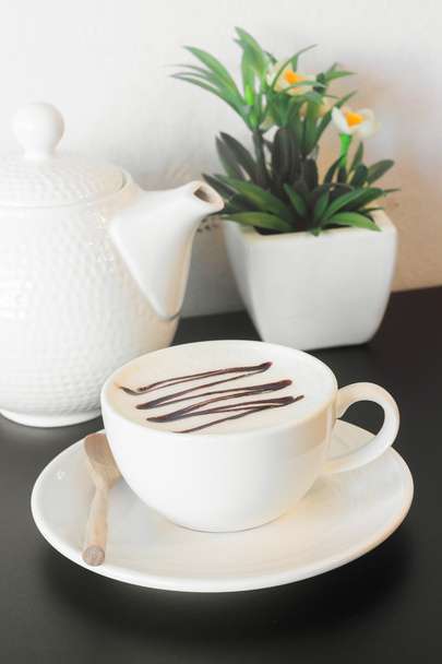 koffiekopje met kruik op zwarte tafel tegen witte concrete wa - Foto, afbeelding