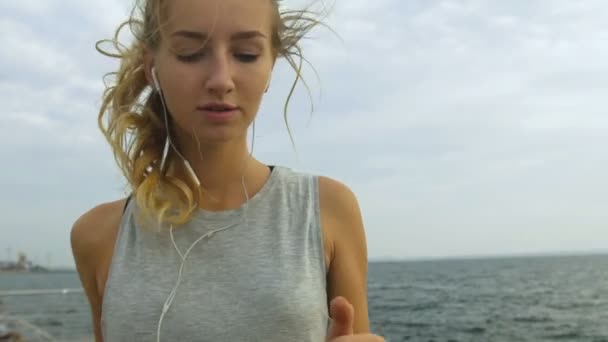 Pretty youngsporty woman jogging near the sea in sunrise light, beautiful sunny background. - Video, Çekim