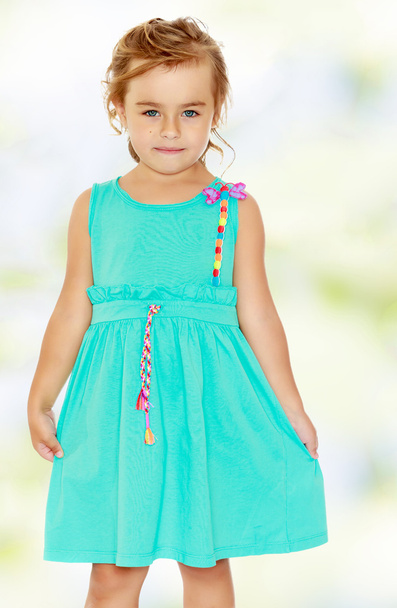 Beautiful little tanned girl in a blue dress. - Фото, изображение