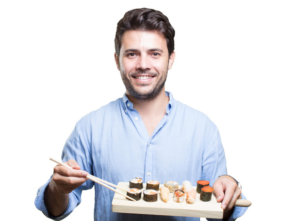 jonge man eten sushi op witte achtergrond - Foto, afbeelding