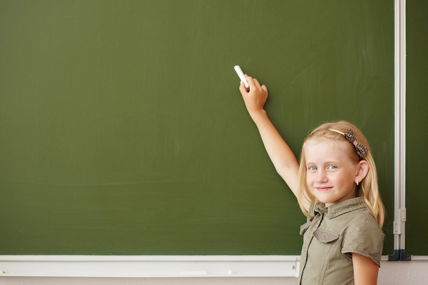 Scoolgirl standing near blackboard - Foto, afbeelding