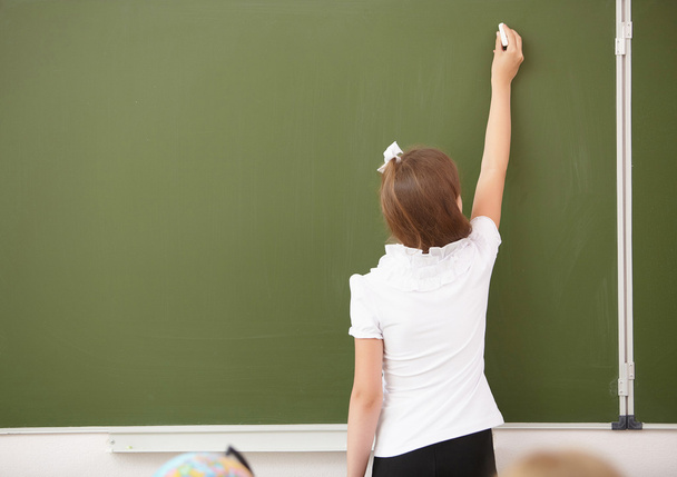 Scoolgirl standing near blackboard - Foto, Imagen