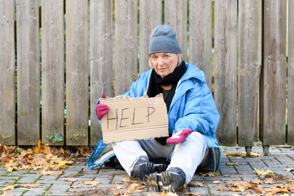 Elderly homeless woman begging on the street - 写真・画像