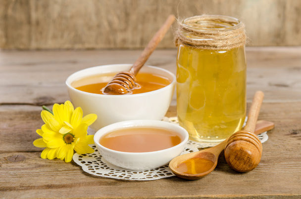 Yellow flower, jar, bowl and spoon with honey on wooden backgrou - Photo, Image
