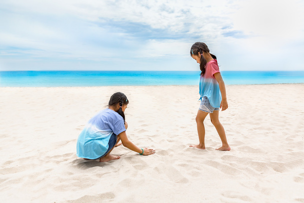 Dos hermanas disfrutar jugando en la playa
 - Foto, Imagen