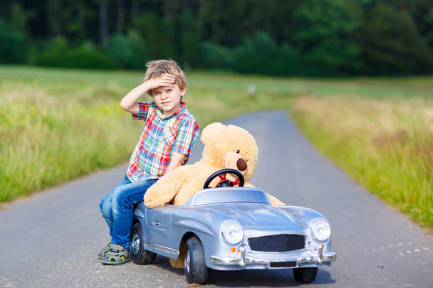 Açık havada büyük oyuncak araba bir ayı ile küçük çocuk çocuk. - Fotoğraf, Görsel