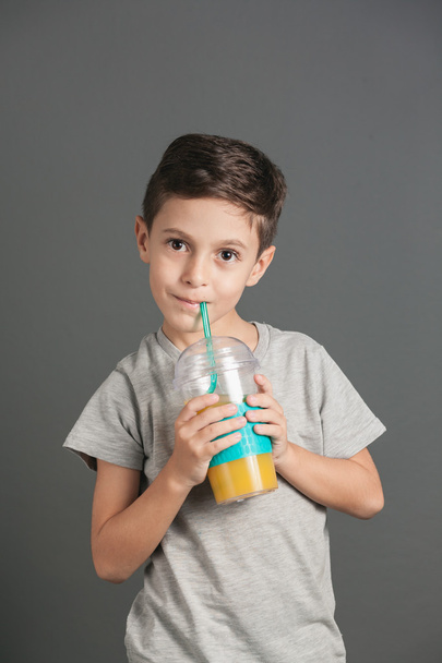 Little funny boy drinking a fresh cola juice through a straw - Foto, Imagem