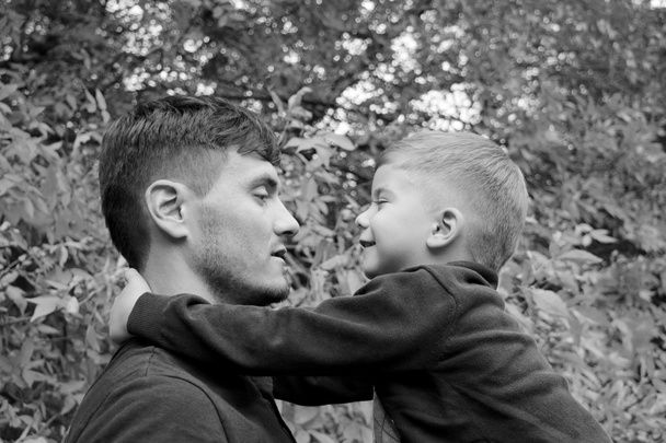 vader heeft zoon in zijn armen, vader en zoon elkaar buiten spelen in het bos - Foto, afbeelding