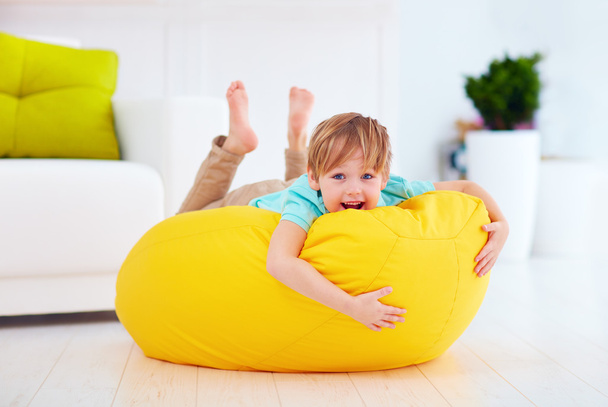 happy kid having fun on yellow bean bag at home - Foto, imagen