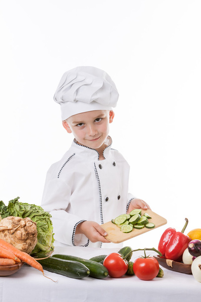 Один маленький мальчик как повар готовит салат, готовит с овощами
 - Фото, изображение