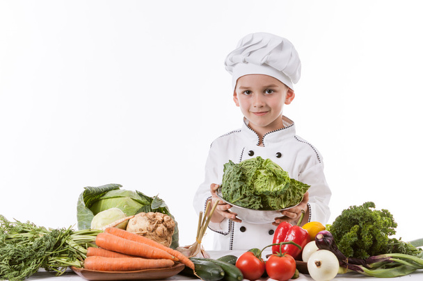 Yksi pieni poika kokkina kokki tekee salaattia, ruoanlaitto vihannesten kanssa
 - Valokuva, kuva