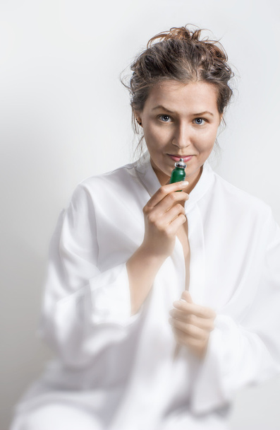 Portrait of young woman in white cloth with small green oil  bot - Foto, Imagen