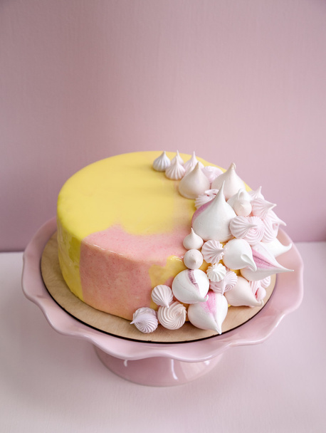 Рожевий торт мусу, покритий жовтим і рожевим шоколадним дзеркалом, глазур'ю та поцілунками меридіани. На рожевій порцеляновій підставці. Рожевий фон. Натуральне світло
. - Фото, зображення