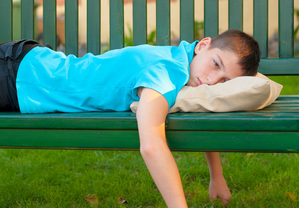 ベンチに横になっている悲しい孤独な 10 代の少年 - 写真・画像