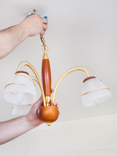 electrician removes ceiling chandelier for repair - 写真・画像