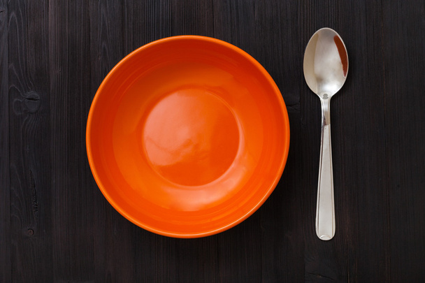 orange bowl and spoon on dark brown table - 写真・画像