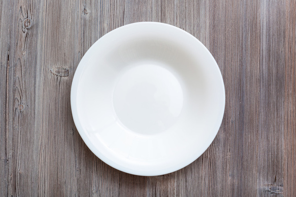 above view of white deep plate on gray brown table - Φωτογραφία, εικόνα