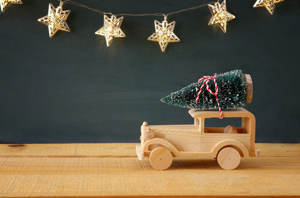 Wooden car carrying a christmas tree - Foto, imagen