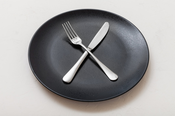 placa negra con cuchillo de cruce, cuchara sobre blanco
 - Foto, imagen