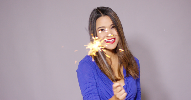 Beautiful woman holding a burning sparkler - Materiał filmowy, wideo
