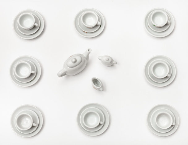 above view cups with saucers and teapot on white - Foto, immagini