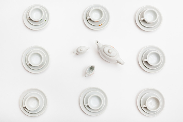 top view of cups with saucers and teapot on white - Fotografie, Obrázek