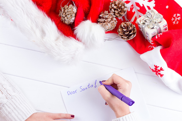 Kobieta, pisząc listy życzeń w notesie w pobliżu prezenty świąteczne - Zdjęcie, obraz