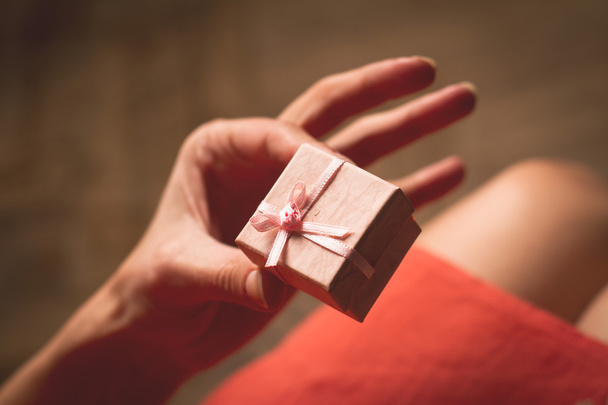 Mujer sosteniendo en su mano una caja de regalo rosa muy pequeña por encima de su k
 - Foto, imagen